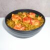 A bowl of yellow rice with four shrimp.