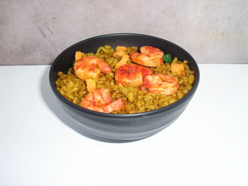 A bowl of yellow rice with four shrimp.